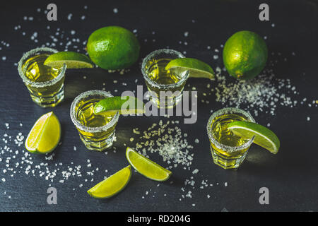 Mexican Gold Tequila shot with lime and salt on black stone table surface, selective focus, shallow depth of the field, copy space. Stock Photo