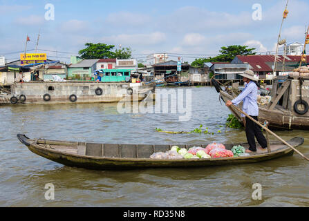 Man selling vegetables from a small traditional boat in the floating market on Hau River. Can Tho, Mekong Delta, Vietnam, Asia Stock Photo