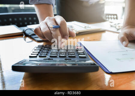 Businessman's hands using calculator and Financial data analyzing on wooden desk at the office Stock Photo