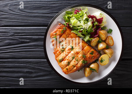 Healthy lunch grilled swordfish fillet with fried potatoes and fresh salad close-up on a plate on a wooden table. horizontal top view from above Stock Photo