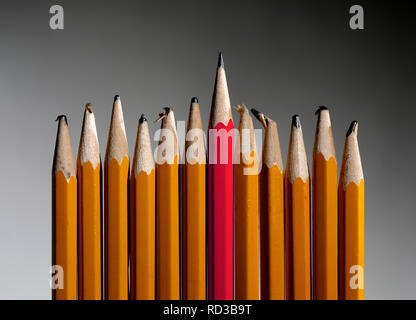 Sharp red pencil standing out from blunt yellow pencils Stock Photo