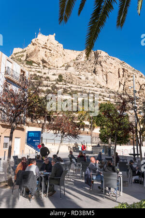 People sitting outside in a restaurant with the castle above, Alicante, Spain, Europe Stock Photo
