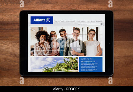 The website of Allianz insurance is seen on an iPad tablet, which is resting on a wooden table (Editorial use only). Stock Photo