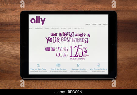 The website of Ally bank is seen on an iPad tablet, which is resting on a wooden table (Editorial use only). Stock Photo