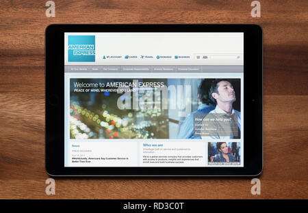 The website of American Express is seen on an iPad tablet, which is resting on a wooden table (Editorial use only). Stock Photo