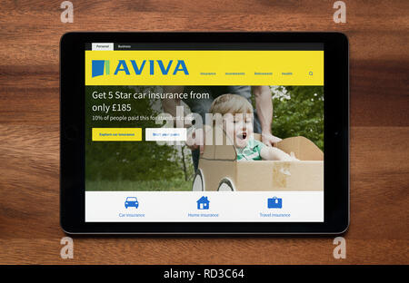 The website of Aviva insurance is seen on an iPad tablet, which is resting on a wooden table (Editorial use only). Stock Photo