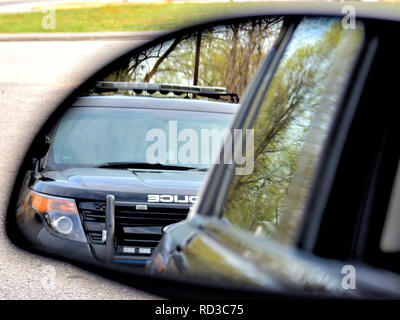 A police car has a motorist stopped. The drivers view from the side view   mirror. Stock Photo