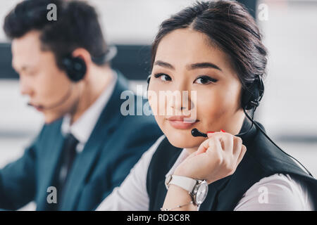 beautiful young kazakh woman in headset smiling at camera at workplace Stock Photo