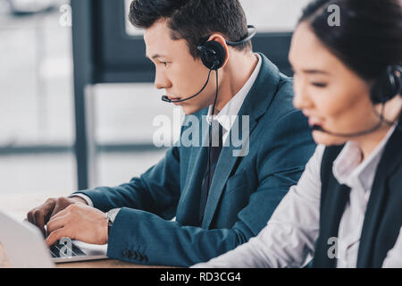 young kazakh coworkers in headsets working together in call center Stock Photo