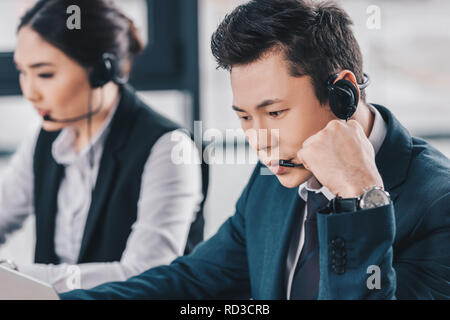 young call center operators in headsets working in office Stock Photo