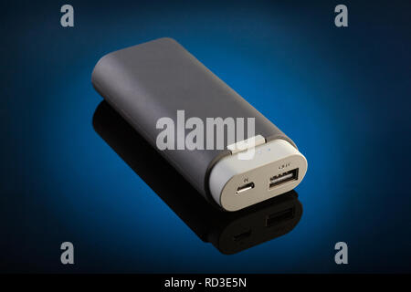 External battery for mobile devices  over dark blue background. Stock Photo