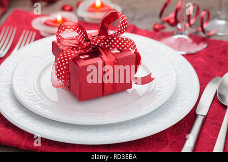 Place setting and gift on holiday table . Stock Photo