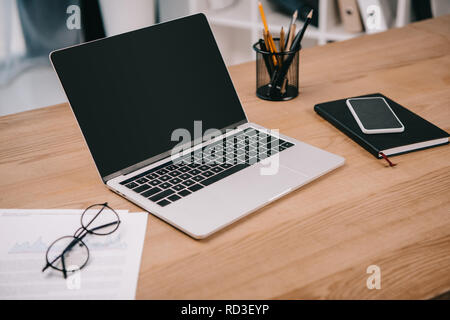 laptop with blank screen, business documents, smartphone and office supplies at workplace Stock Photo