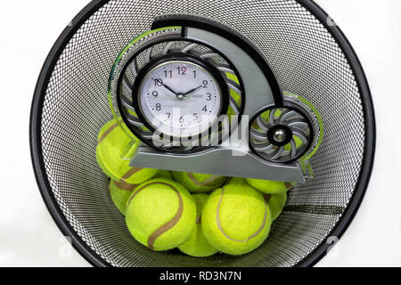 Tennis balls and a clock in a trash can Stock Photo