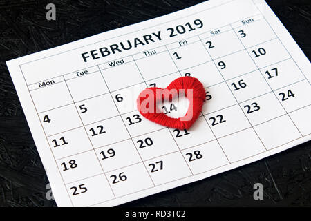 Calendar page with red hearts on February 14, Valentine's Day on a black background. Valentines day greeting card Stock Photo