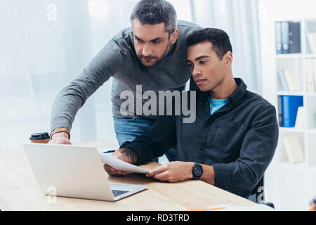 two focused businessmen working with papers and laptop in office Stock Photo