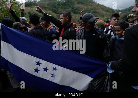 Aguas Calientes, Guatemala. 16th Jan, 2019. Migrants hold their identity cards high as they reach the Aguas Calientes border crossing between Honduras and Guatemala. A so-called migrant caravan had left the Honduran city of San Pedro Sula to the north. According to the government of Honduras, 700 people entered Guatemala with and without the necessary papers. The group plans to immigrate to the USA. Credit: Morena Perez Joachin/dpa/Alamy Live News Stock Photo