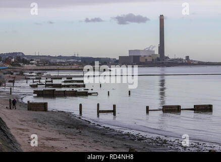 Carrickfergus, County Antrim, Northern Ireland. 17 January 2019. UK weather - grey cloud over Carrickfergus on a cold but calm day on Belfast Lough. Man walking dog on shore at Carrickfergus with Kilroot power station in background. Credit: David Hunter/Alamy Live News. Stock Photo