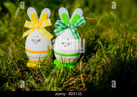 Cute creative photo with easter eggs as the Easter Bunny on green grass background. Happy easter greeting card.A Bunny Easter egg.Easter holiday concept with two cute handmade eggs: bunnies Stock Photo