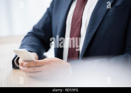 mid section of businessman in formal wear using smartphone Stock Photo