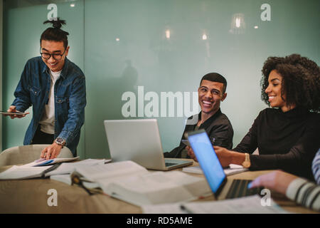 Group of multi-ethnic students sitting around table with books and laptop at classroom. Group of university students studying together at educational Stock Photo