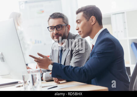 two professional businessmen discussing and using desktop computer in office Stock Photo