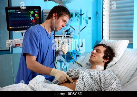 Male intensive care nurse looking after a patient lying in a special bed, medical treatment and artificial respiration of the Stock Photo