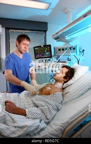 Male intensive care nurse looking after a patient lying in a special bed, medical treatment and artificial respiration of the Stock Photo
