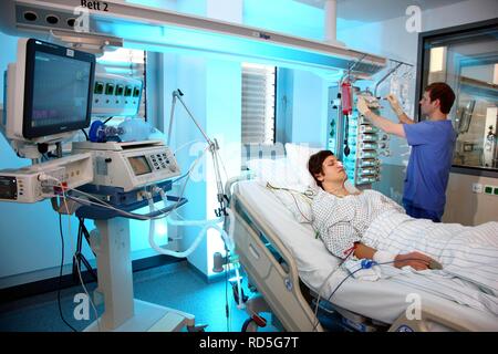 Male intensive care nurse looking after a patient lying in a special bed, medical treatment and artificial respiration of the Stock Photo