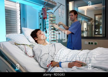 Male intensive care nurse looking after a patient lying in a special bed, medical treatment and artificial respiration of the Stock Photo