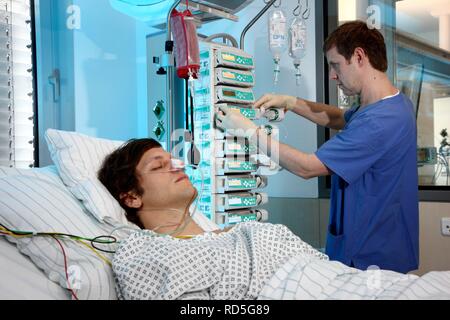 Male intensive care nurse looking after a patient lying in a special bed, medical treatment and artificial respiration of the Stock Photo