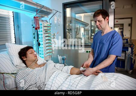 Male intensive care nurse looking after a patient lying in a special bed, medical treatment and artificial respiration of the Stock Photo