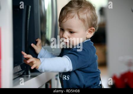 Little boy, 1 year, exploring a DVD player Stock Photo