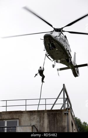 Hostage situation exercise, a special response unit enters a buildig by rappelling or fast roping from a helicopter, training Stock Photo