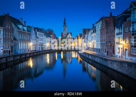 Beautiful panoramic view of famous Spiegelrei canal with famous Poortersloge and Jan van Eyck square in the background illuminated during blue hour at Stock Photo