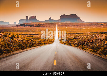 Classic panorama view of historic U.S. Route 163 running through famous Monument Valley in beautiful golden evening light at sunset in summer, Utah, U