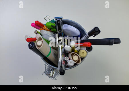 Pencil holder with pens, markers and scissors on a white desk Stock Photo