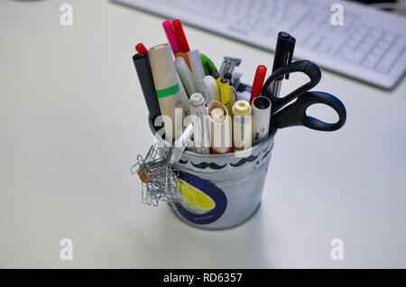 Pencil holder with pens, markers and scissors on a white desk Stock Photo