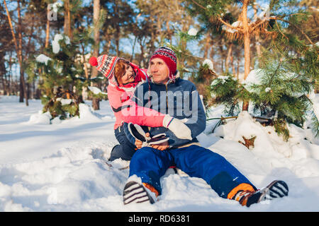 Senior couple hugging in winter forest. Man and woman sitting in snow and having fun on Valentine's Day outdoors Stock Photo