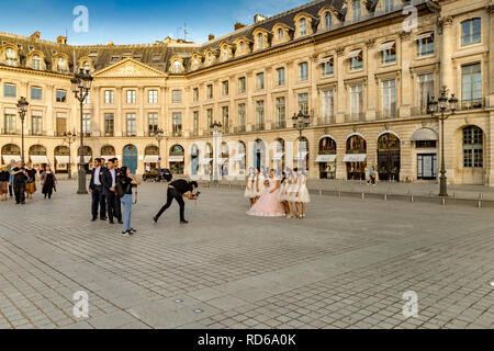 A photographer takes a picture of a  Chinese bride in her wedding dress  with her bridesmaids at her side at  Place Vendome , Paris,France Stock Photo