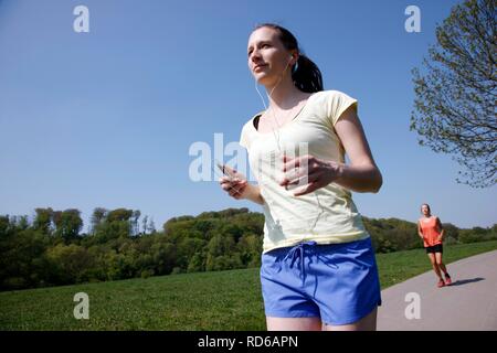 Recreational runner, young woman, 25-30 years, listening to music while jogging Stock Photo