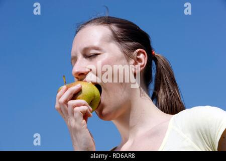 Young woman, 25-30 years, eating an apple after exercise Stock Photo