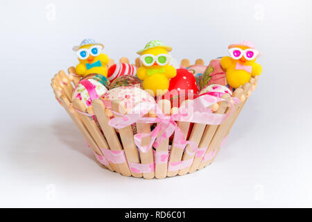 Easter decoration with colorful eggs and funny chicks in wooden basket isolated on white background. Easter holiday concept. Stock Photo