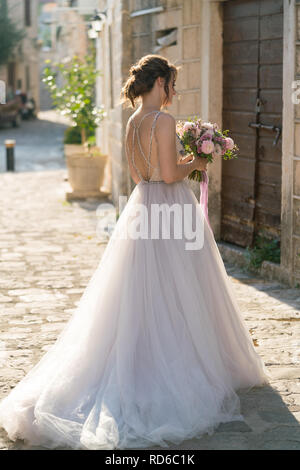 beautiful bride in a white dress stands outdoors Stock Photo