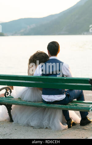 newlyweds sit on a bench on the pier and admire the sea Stock Photo