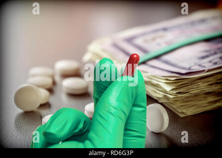 Hand with green glove latex holds red capsule, concept sanitary copayment, conceptual image Stock Photo