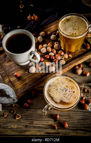 Homemade hazelnut coffee latte or cappuccino, rustic wooden background with hazelnuts, three coffee cups copy space Stock Photo