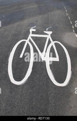 White painted stylized bicycle emblem on a paved bike lane alongside a main road in British Columbia, Canada. Stock Photo