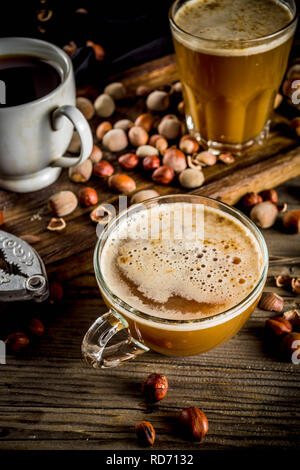 Homemade hazelnut coffee latte or cappuccino, rustic wooden background with hazelnuts, three coffee cups copy space Stock Photo