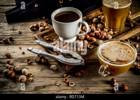 Homemade hazelnut coffee latte or cappuccino, rustic wooden background with hazelnuts, three coffee cups copy space Stock Photo